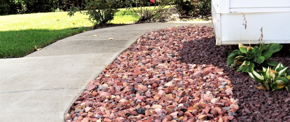 Red rock ground covering for landscape bed in New Albany, IN.